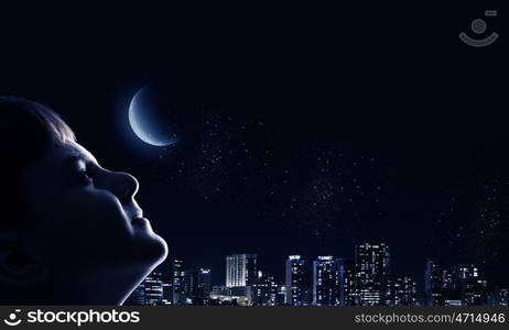 Little dreamer. Cute boy of school age against night background