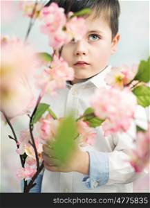 Little elegant boy holding a pink flower