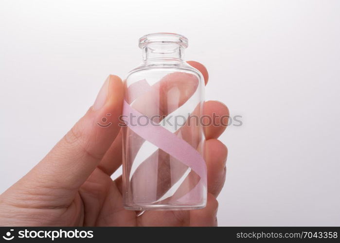 Little empty glass bottle in hand on a white background