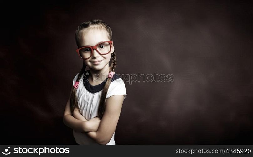 Little genius. Little cute girl of school age in glasses against blackboard