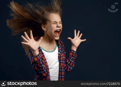 Little girl against powerful airflow in studio, developing hairstyle effect. Children and wind, kid isolated on dark background, child emotion. Little girl against powerful airflow in studio