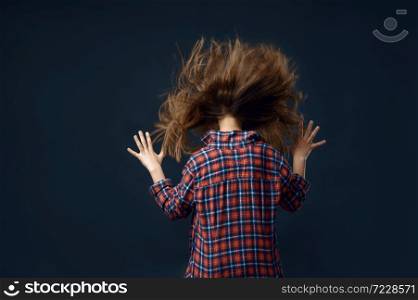 Little girl against powerful airflow in studio, developing hairstyle effect. Children and wind, kid isolated on dark background, child emotion. Little girl against powerful airflow in studio
