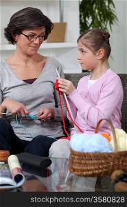 little girl and grandmother knitting together