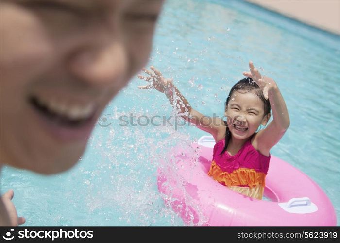 Little girl and her father splashing in the pool