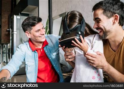 Little girl and her parents playing video games with VR glasses at home. Family concept.