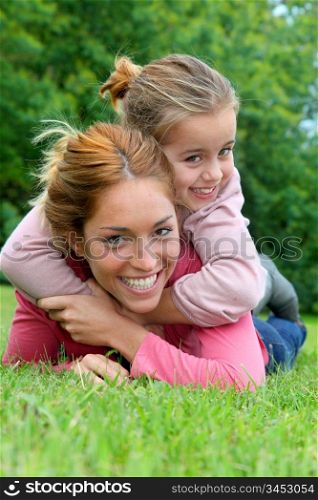 Little girl and mother laying on grass in park