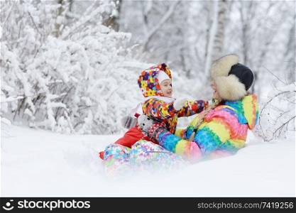 little girl and mother sit and play in the snow in the park