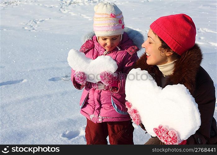 Little girl and mother with snowy hearts