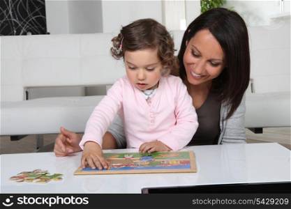 Little girl and woman doing puzzle