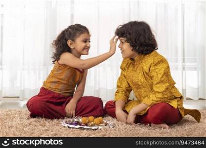 Little Girl applying tika on forehead of her brother on the occasion of Bhai Dooj