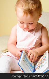 Little girl are reading the book, sitting on the sofa