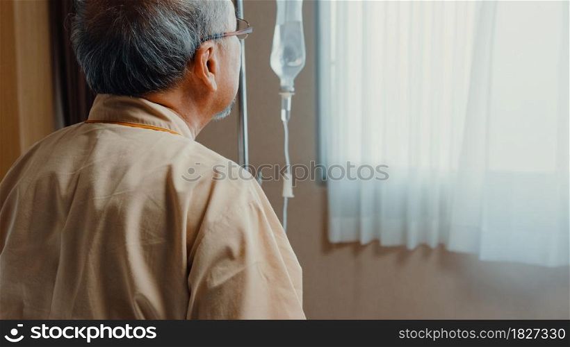 Little girl Asian granddaughter visiting hug sick senior grandfather hospitalized sit on hospital bed in patient room. Rehabilitation activity, health insurance, healthcare and medicine concept.