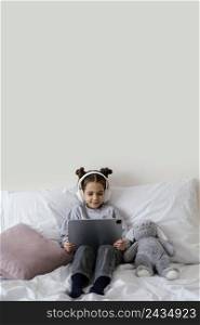 little girl bed with headphones using tablet 3