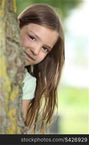 Little girl behind a tree