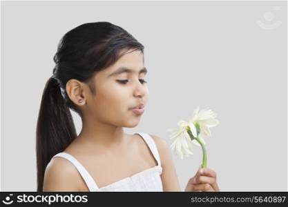 Little girl blowing on petals of a flower