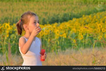 Little girl blowing soap bubbles on field