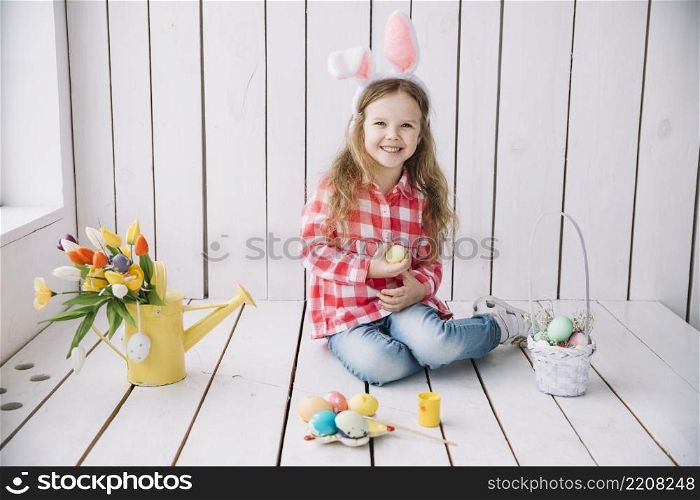 little girl bunny ears sitting floor with colored eggs
