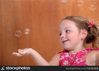 Little girl catching bubbles