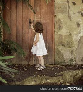 Little girl checking the old, wooden door