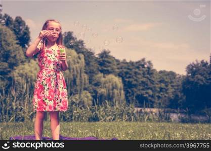 Little girl child blowing soap bubbles outdoor.. Little girl child blowing soap bubbles outdoor. Kid having fun in park. Happy and carefree childhood. Instagram filtered.