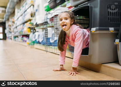 Little girl chooses carrier for puppy in pet shop. Kid plays in petshop, goods for domestic animals