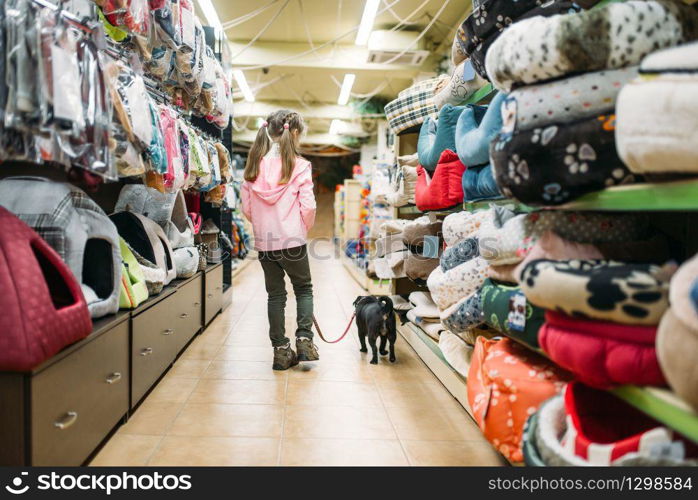 Little girl chooses house for puppy in pet shop. Kid plays in petshop, goods for domestic animals. Little girl chooses house for puppy in pet shop