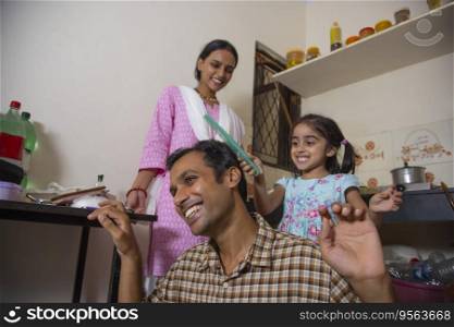 Little girl combing her father s hair in the kitchen while mother standing behind