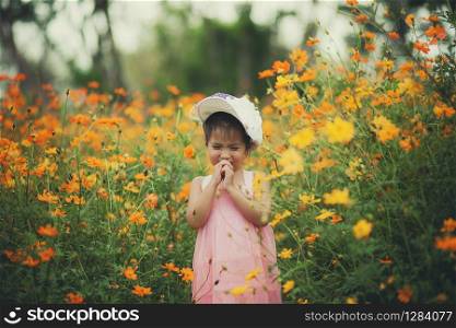 little girl crying in yellow cosmos flower blooming field