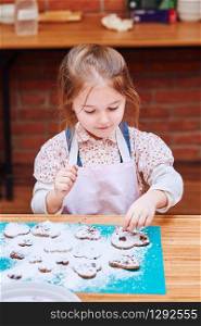 Little girl decorating her baked cookies with colorful sprinkle and icing sugar. Kid taking part in baking workshop. Baking classes for children, aspiring little chefs. Learning to cook. Combining and stirring prepared ingredients. Real people, authentic situations