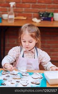 Little girl decorating her baked cookies with colorful sprinkle and icing sugar. Kid taking part in baking workshop. Baking classes for children, aspiring little chefs. Learning to cook. Combining and stirring prepared ingredients. Real people, authentic situations