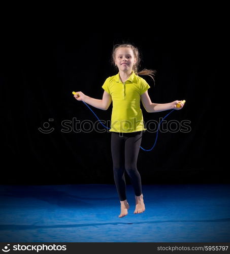 Little girl doing gymnastic exercises on black