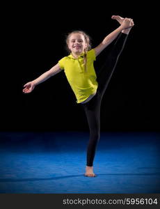 Little girl doing gymnastic exercises on black