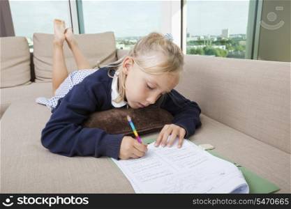 Little girl doing mathematics homework on sofa