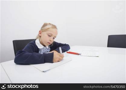 Little girl drawing on paper with felt tip pen at table