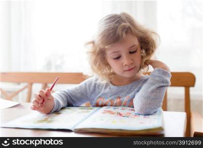 Little girl drawing with pencils and learning at home
