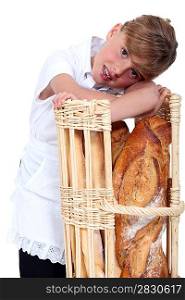 little girl dressed in baker reposing on a bread bin