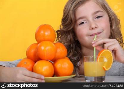Little girl drinking freshly squeezed orange juice