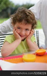 Little girl drinking juice in the garden