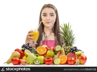 Little girl drinking orange juice. Little girl with fruits - Happy girl with fruits assortment on the table.