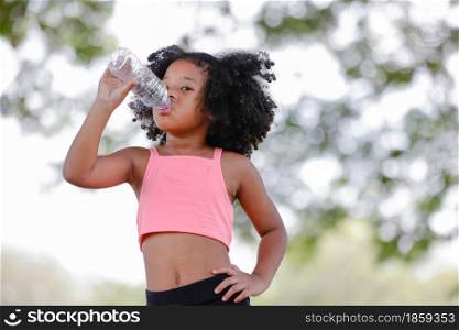 Little girl drinking water from plastic bottles after exercise at outdoor