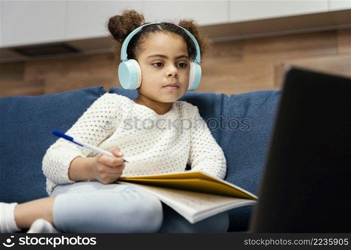 little girl during online school with laptop headphones