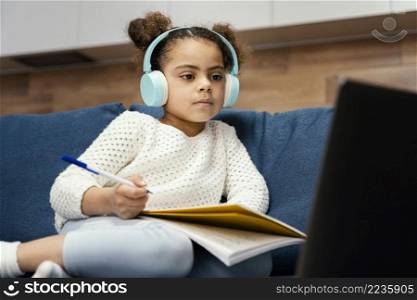 little girl during online school with laptop headphones