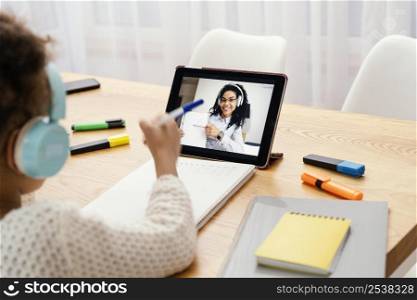 little girl during online school with tablet headphones