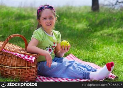 Little girl eating apple at picnic in the woods