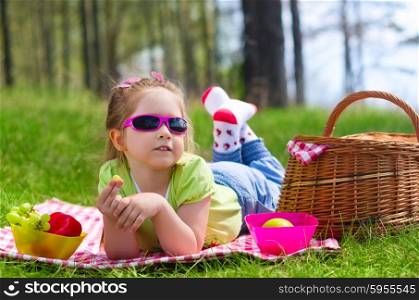 Little girl eating grapes at picnic in the woods