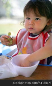 Little girl eating grapes from a bowl