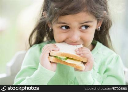 Little girl eating sandwich at home