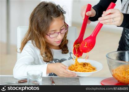 Little girl eating spaghetti at home