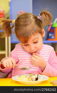 Little girl eats in kindergarten