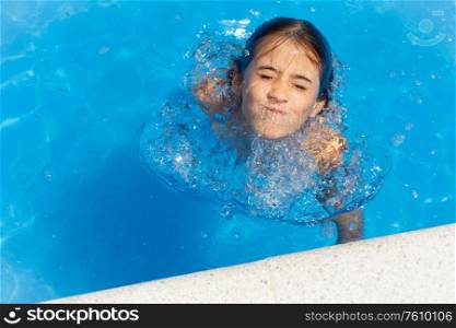 Little girl eight years old playing in a swimming pool.. Cute girl eight years old playing in a swimming pool.
